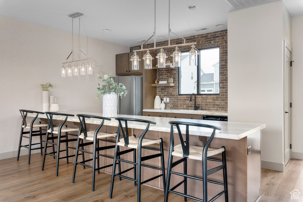 Kitchen featuring light hardwood / wood-style flooring, stainless steel fridge, a breakfast bar area, and a kitchen island
