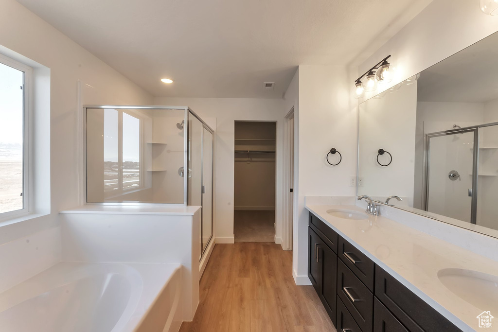 Bathroom featuring double vanity, plus walk in shower, and hardwood / wood-style floors