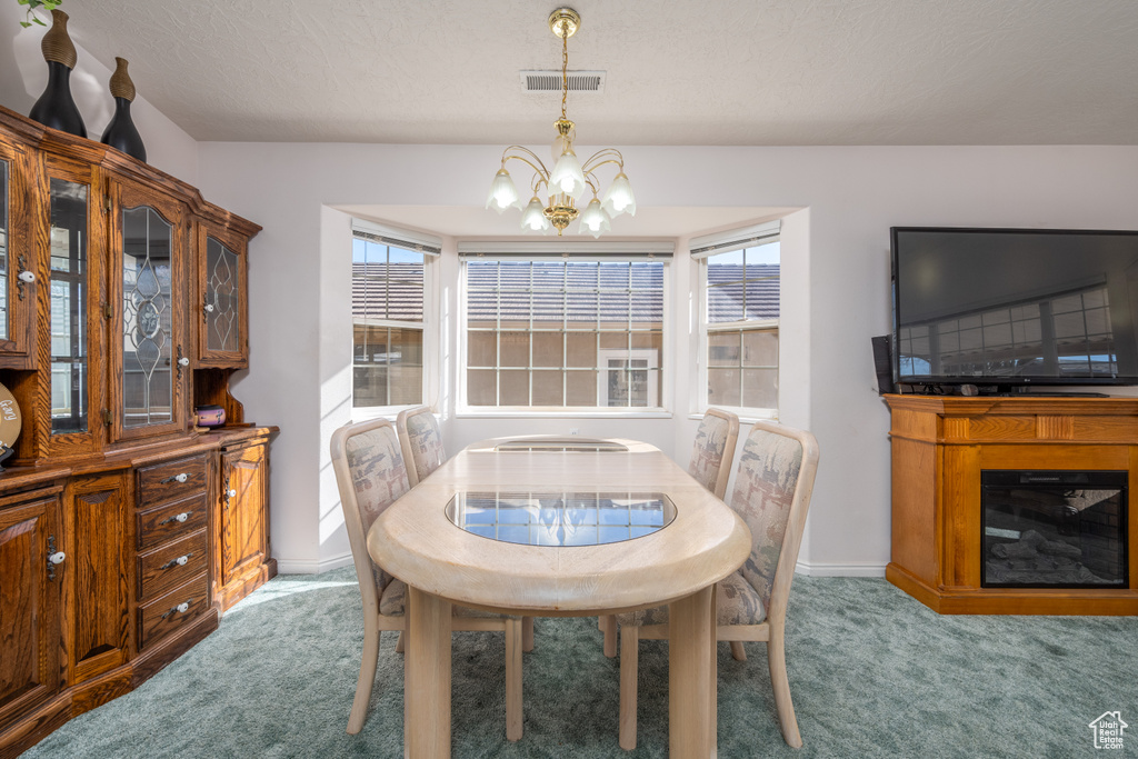Carpeted dining room featuring a chandelier and a wealth of natural light
