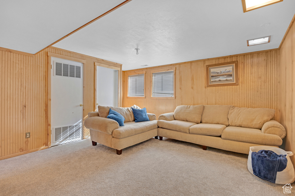 Carpeted living room featuring wood walls