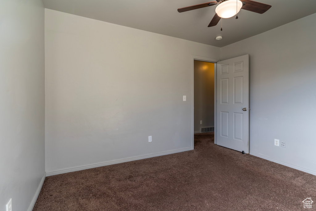 Spare room with ceiling fan and dark carpet