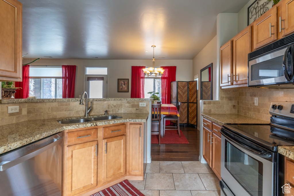 Kitchen featuring backsplash, sink, a notable chandelier, stainless steel appliances, and light tile flooring