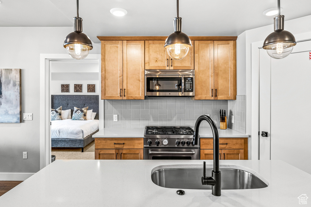 Kitchen with sink, tasteful backsplash, appliances with stainless steel finishes, and decorative light fixtures