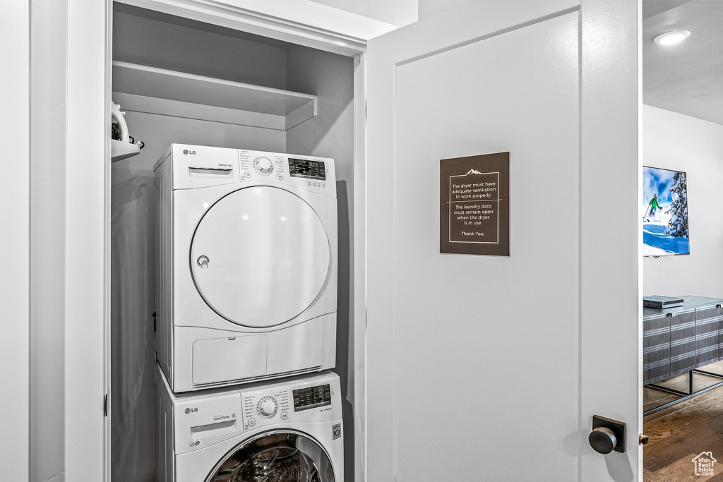 Washroom featuring stacked washer and dryer and hardwood / wood-style floors