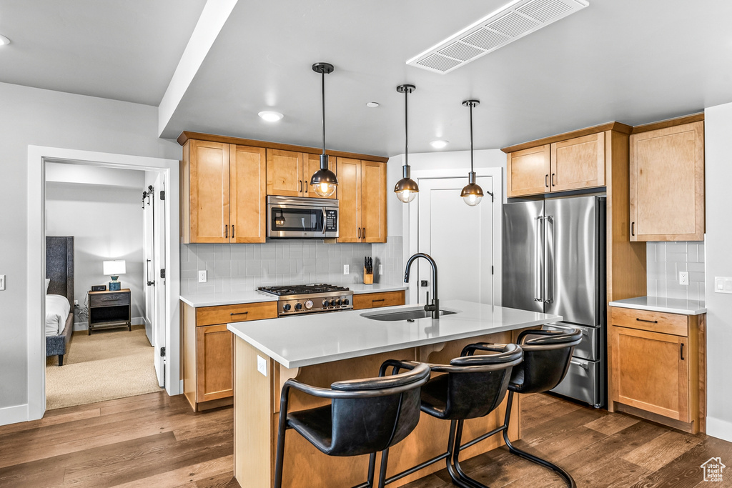 Kitchen with decorative light fixtures, stainless steel appliances, backsplash, sink, and carpet flooring