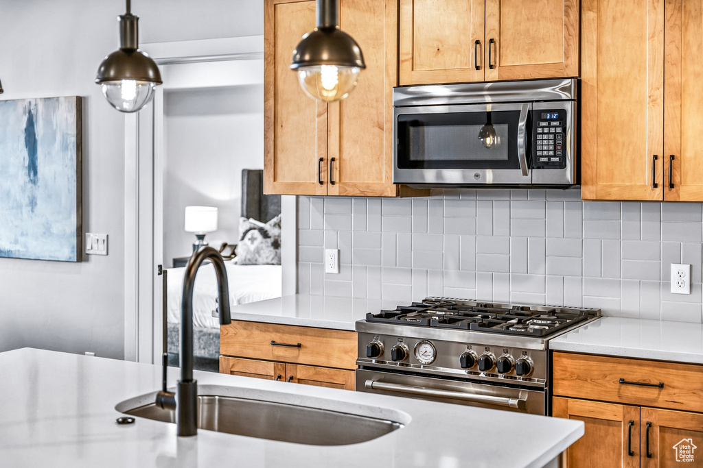 Kitchen featuring sink, stainless steel appliances, tasteful backsplash, and decorative light fixtures
