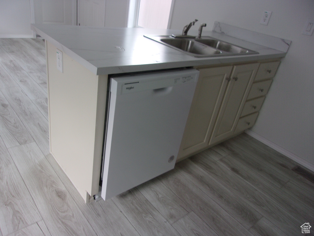 Kitchen with sink, white dishwasher, and light hardwood / wood-style floors