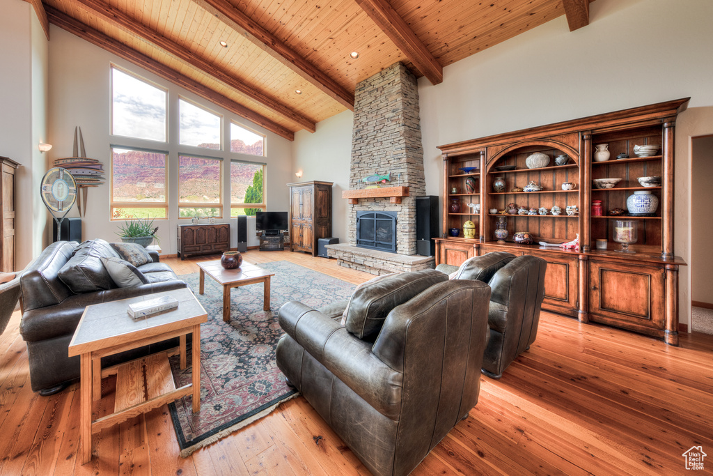 Living room with beamed ceiling, light hardwood / wood-style floors, a fireplace, and wooden ceiling