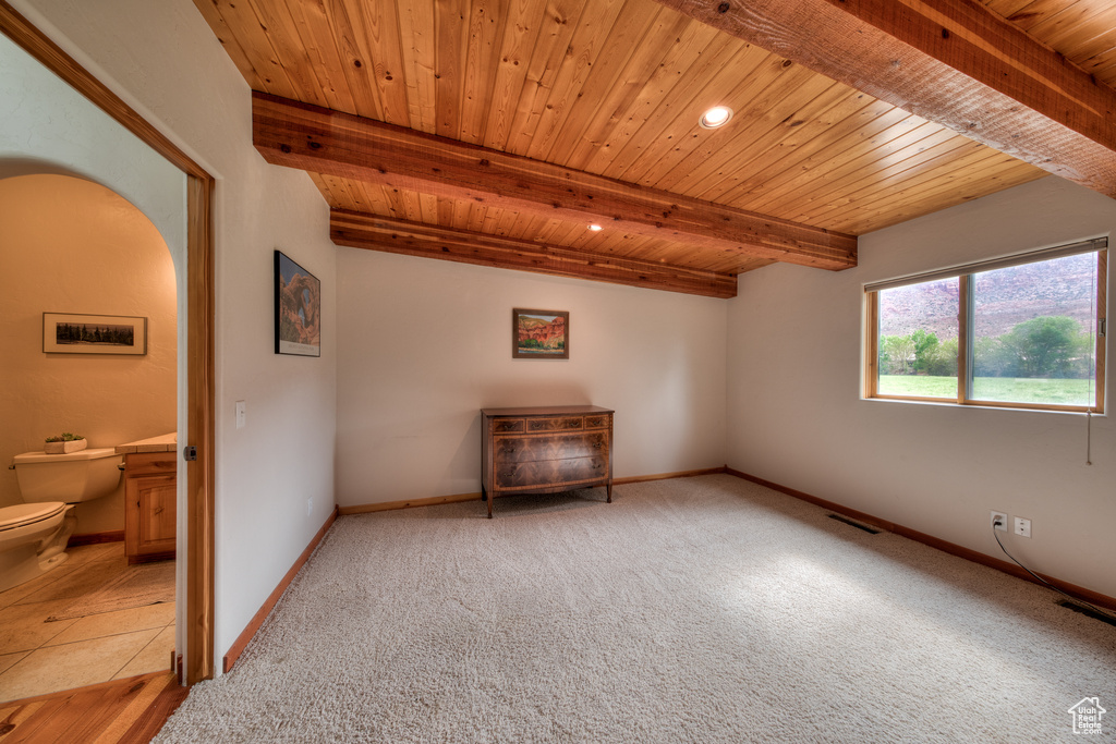 Carpeted spare room featuring wood ceiling and beam ceiling