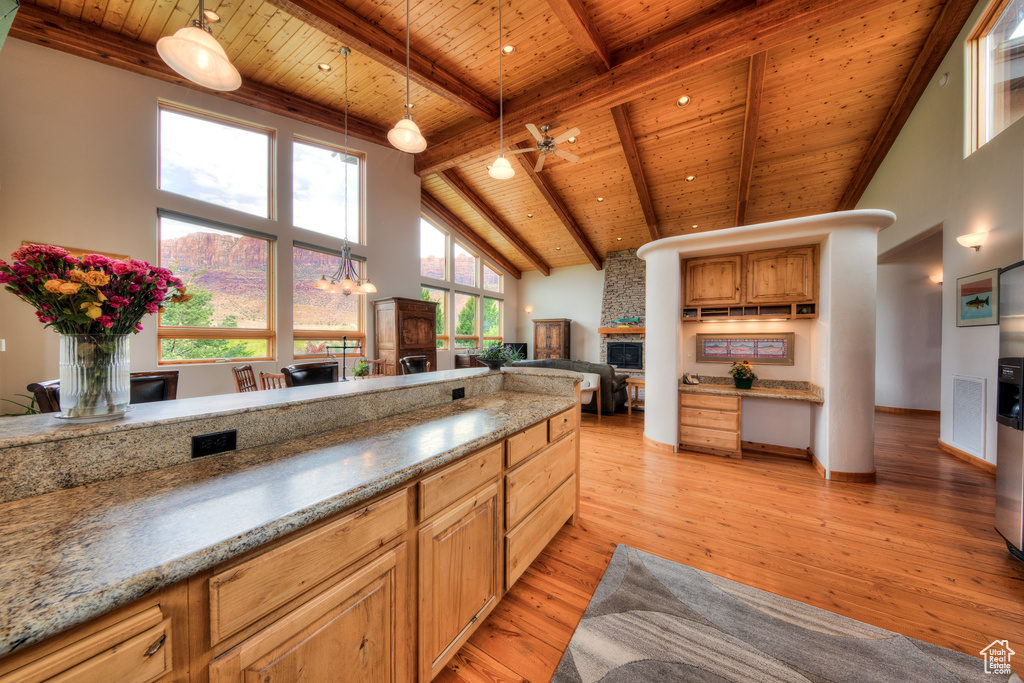 Kitchen featuring light hardwood / wood-style floors, pendant lighting, wood ceiling, ceiling fan with notable chandelier, and beamed ceiling
