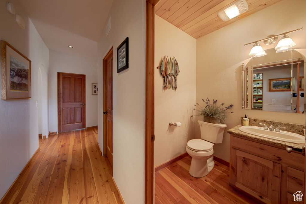 Bathroom with wood-type flooring, toilet, vanity, and wood ceiling