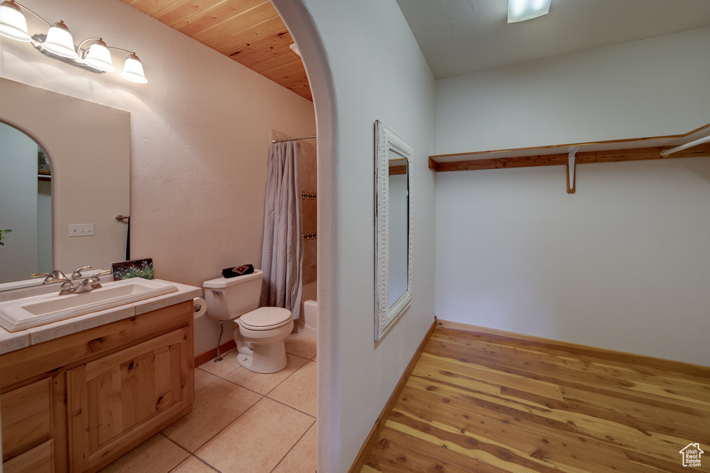 Full bathroom featuring toilet, vanity with extensive cabinet space, shower / bath combo, wood ceiling, and tile flooring