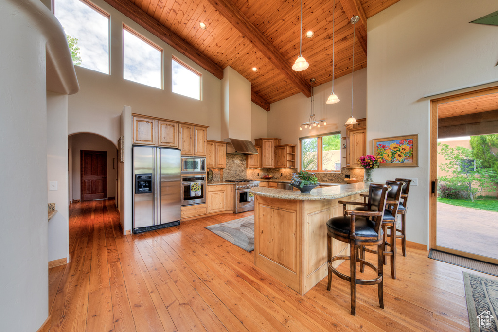 Kitchen with a breakfast bar, high vaulted ceiling, appliances with stainless steel finishes, and wood ceiling