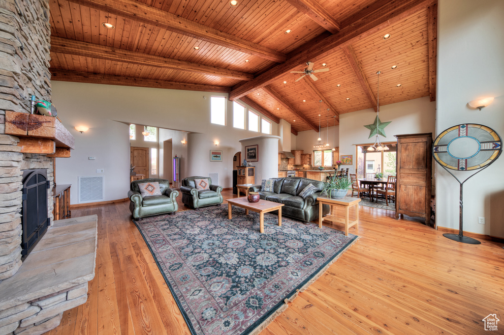 Living room featuring light hardwood / wood-style floors, a fireplace, high vaulted ceiling, and ceiling fan