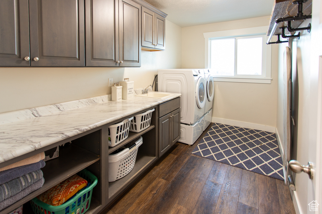 Laundry room featuring washer and dryer, sink, cabinets, and dark hardwood / wood-style floors