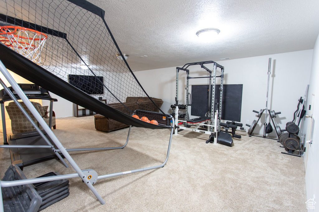 Exercise area with a textured ceiling and light colored carpet