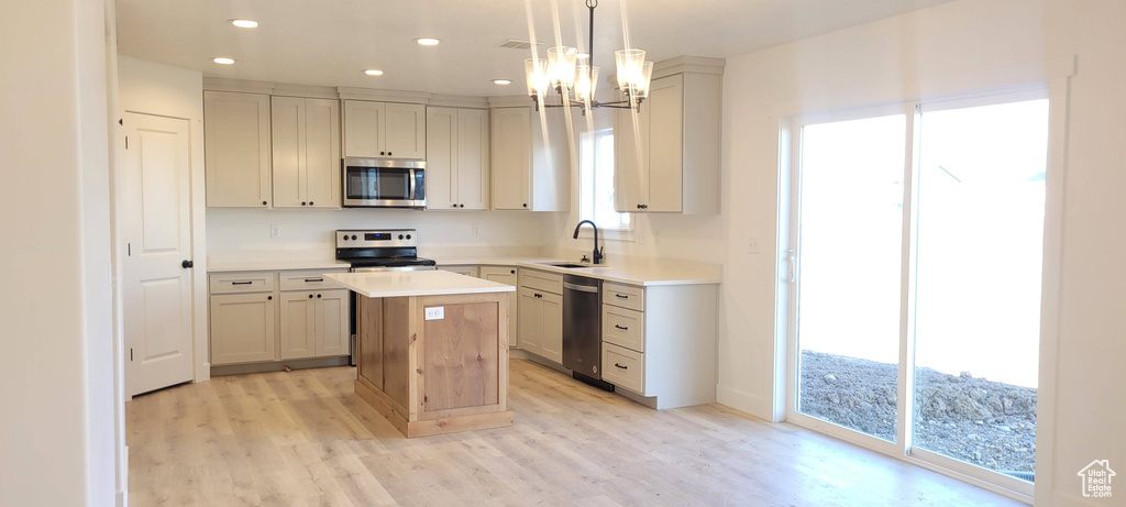 Kitchen with a chandelier, a center island, appliances with stainless steel finishes, hanging light fixtures, and light wood-type flooring