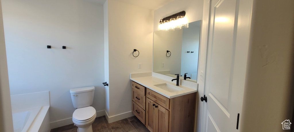 Bathroom featuring a bath, toilet, large vanity, and wood-type flooring