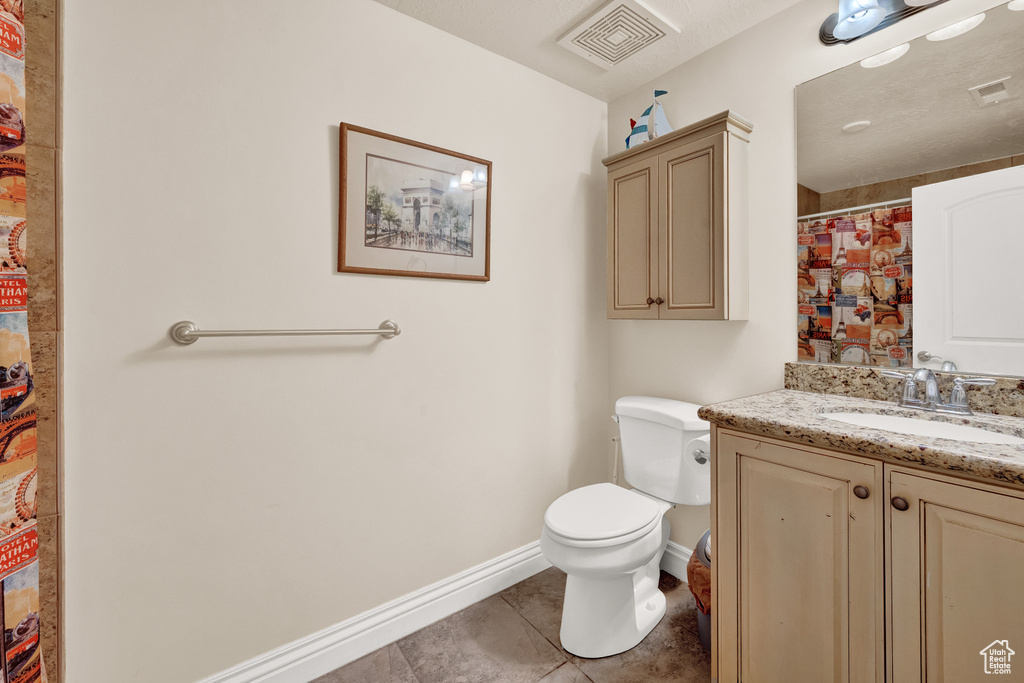 Bathroom with toilet, oversized vanity, and tile flooring
