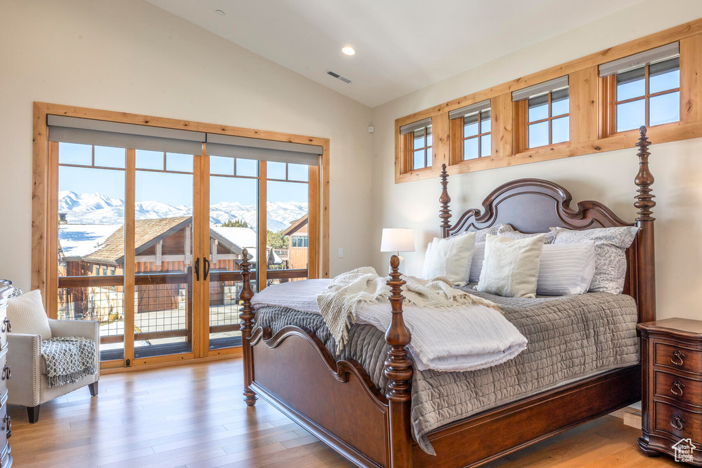 Bedroom with light hardwood / wood-style flooring, lofted ceiling, and access to exterior