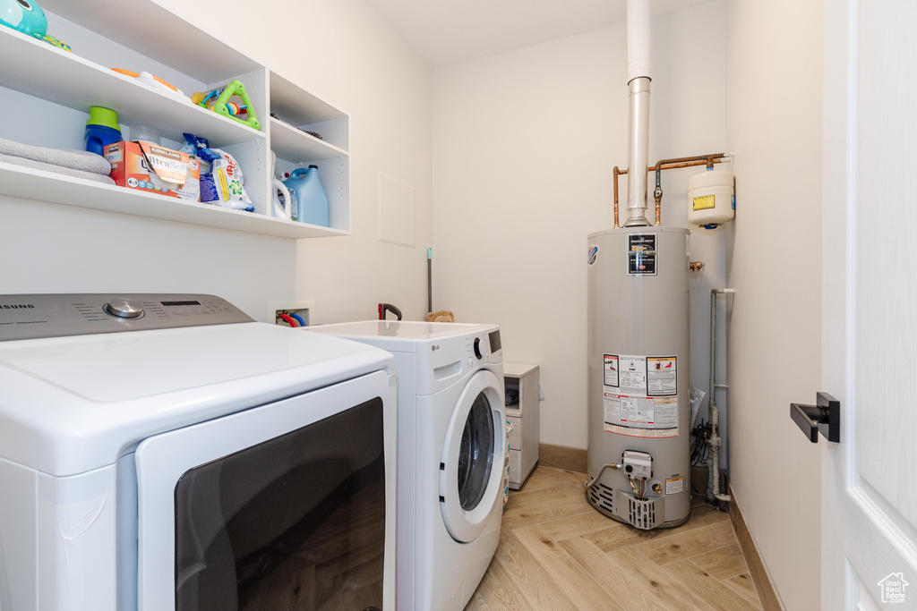 Laundry room with washing machine and clothes dryer, water heater, light parquet flooring, and hookup for a washing machine