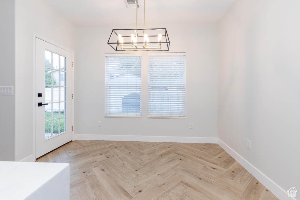 Unfurnished room featuring a notable chandelier and light parquet flooring