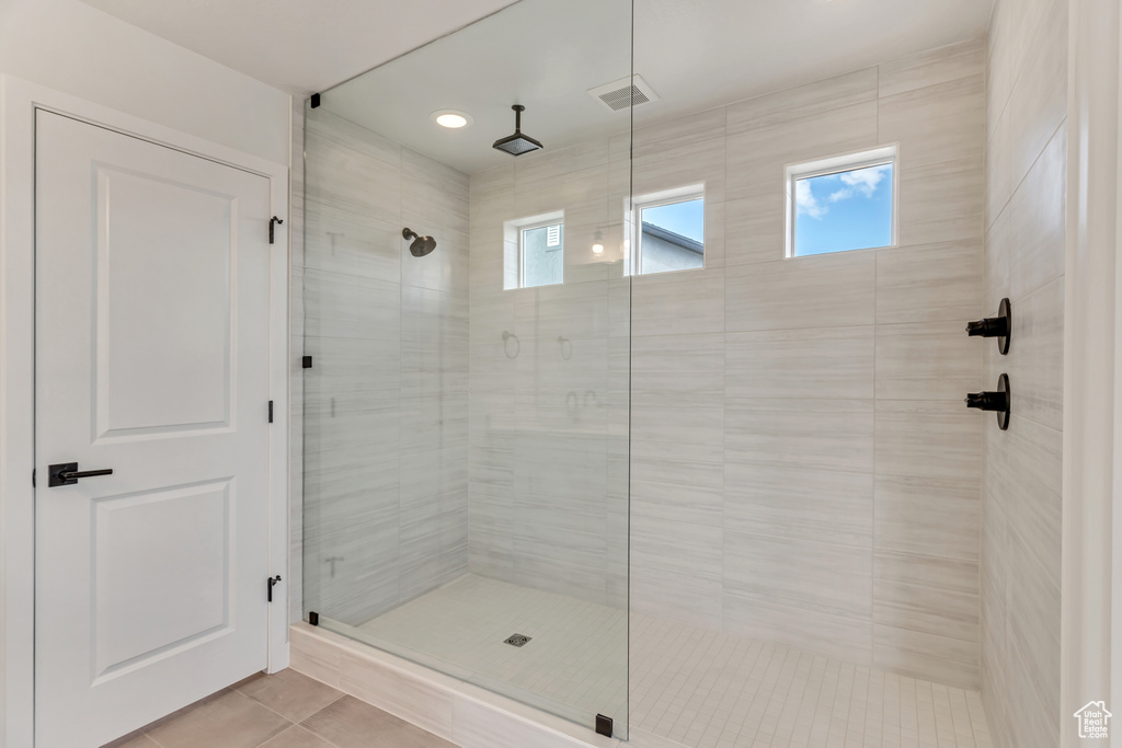 Bathroom with a shower with shower door and tile flooring
