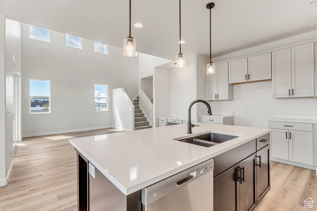 Kitchen featuring a center island with sink, sink, white dishwasher, and pendant lighting