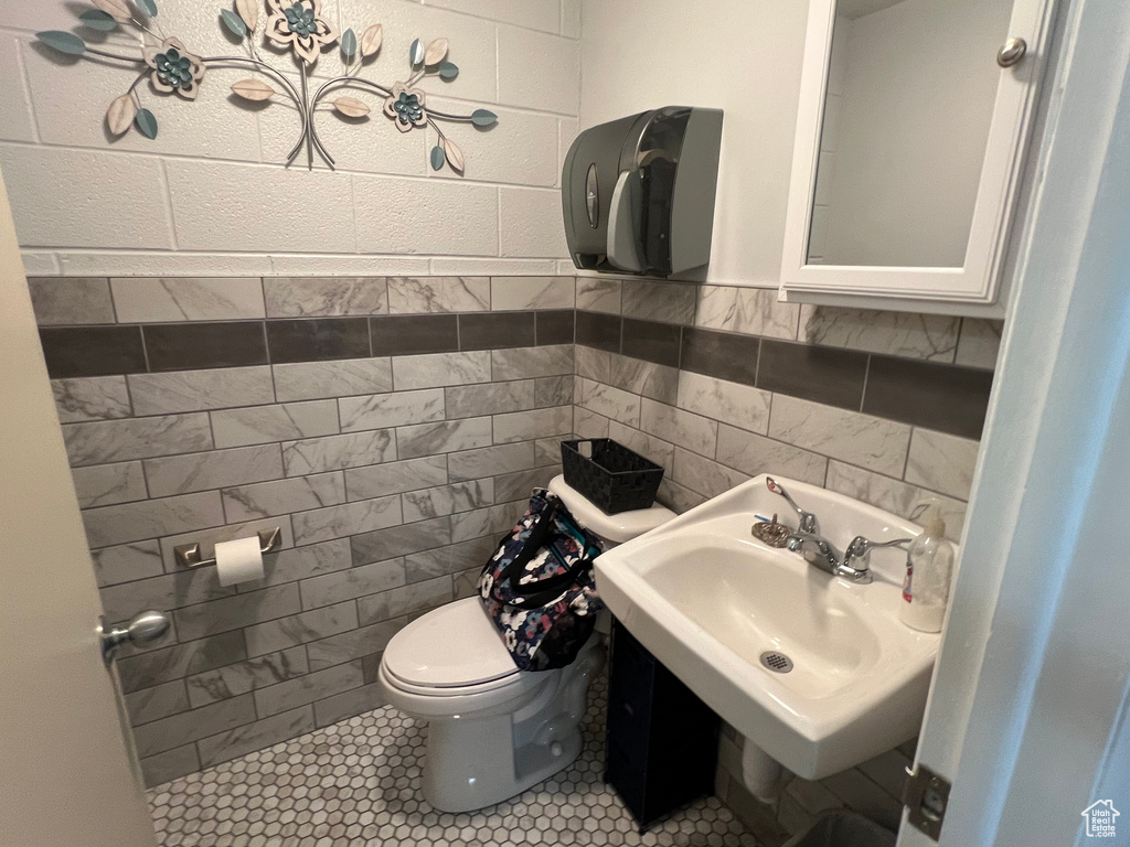 Bathroom featuring sink, tile walls, tile floors, and toilet