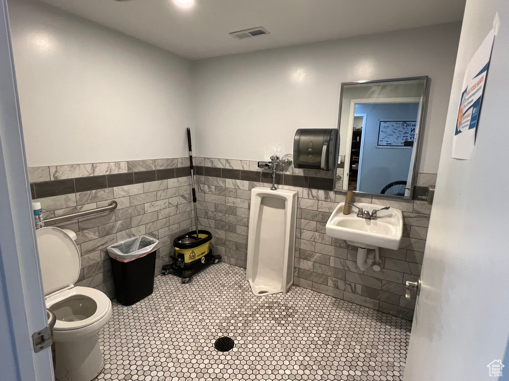 Bathroom featuring sink, tile walls, tile flooring, and toilet