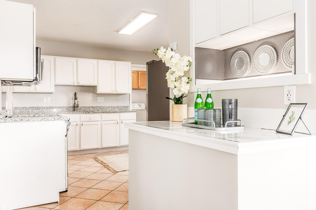 Kitchen with white cabinetry, light tile flooring, sink, and washer / clothes dryer