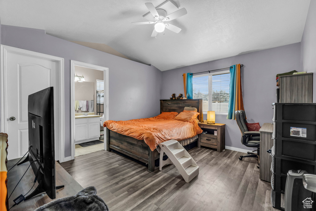 Bedroom featuring dark hardwood / wood-style floors, lofted ceiling, connected bathroom, and ceiling fan