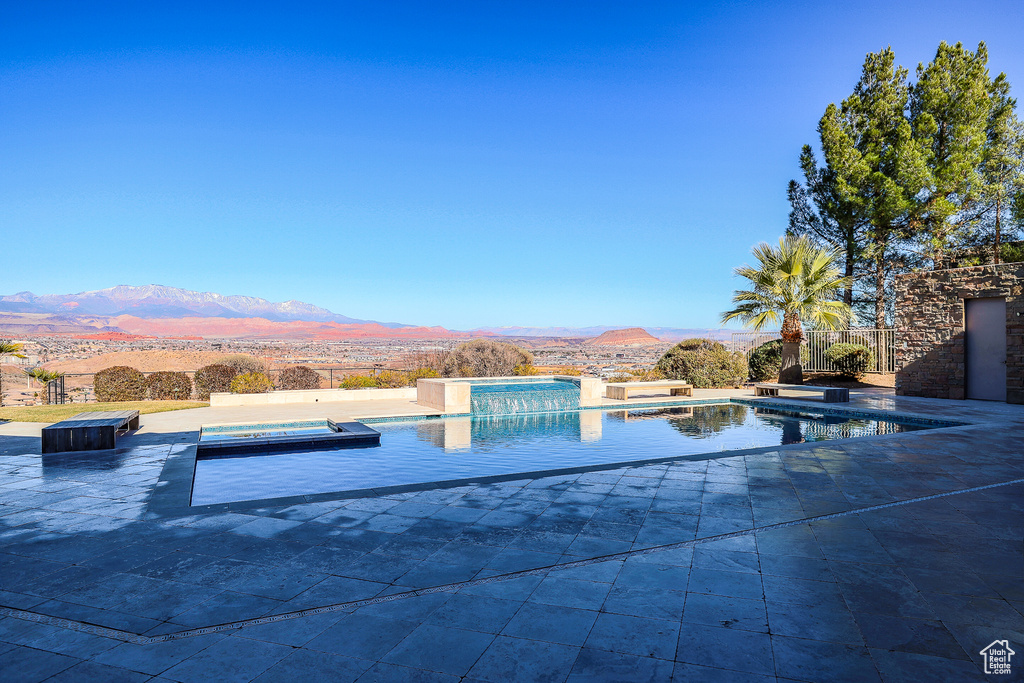 View of pool with a hot tub, a patio area, and a mountain view