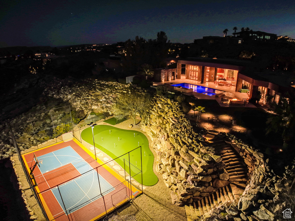 Pool at night featuring tennis court