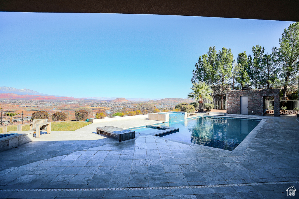 View of pool featuring a jacuzzi, a patio area, and a mountain view