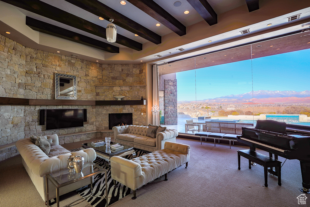 Carpeted living room featuring a stone fireplace, a wealth of natural light, and a mountain view