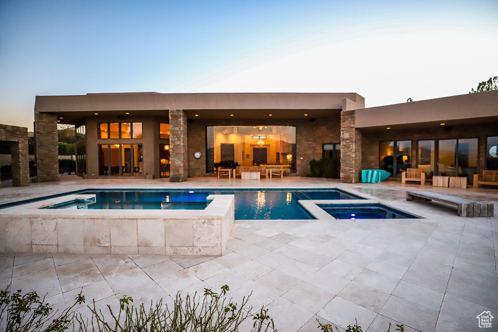 Pool at dusk with an in ground hot tub and a patio area