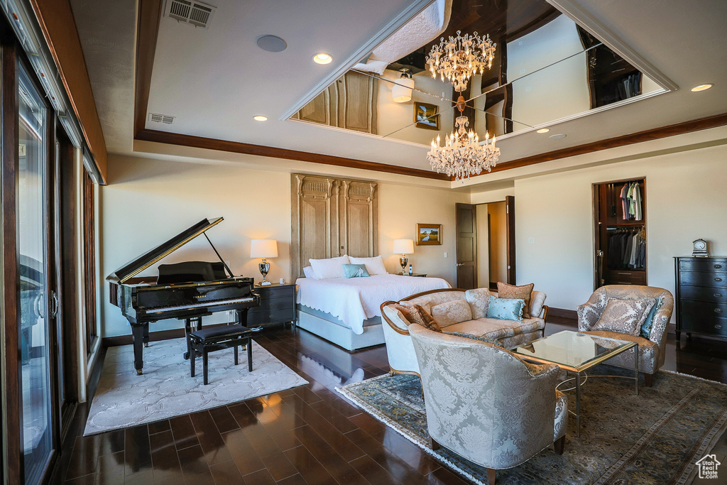 Bedroom with a tray ceiling, a notable chandelier, and dark hardwood / wood-style floors