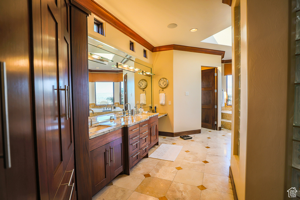 Bathroom featuring tile floors, double vanity, ornamental molding, and a bath to relax in