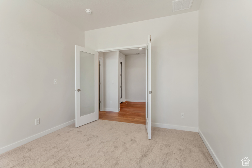 Unfurnished bedroom featuring french doors and light colored carpet