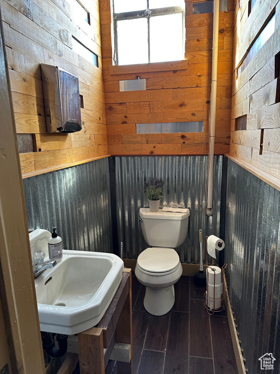 Bathroom with sink, toilet, and wooden walls