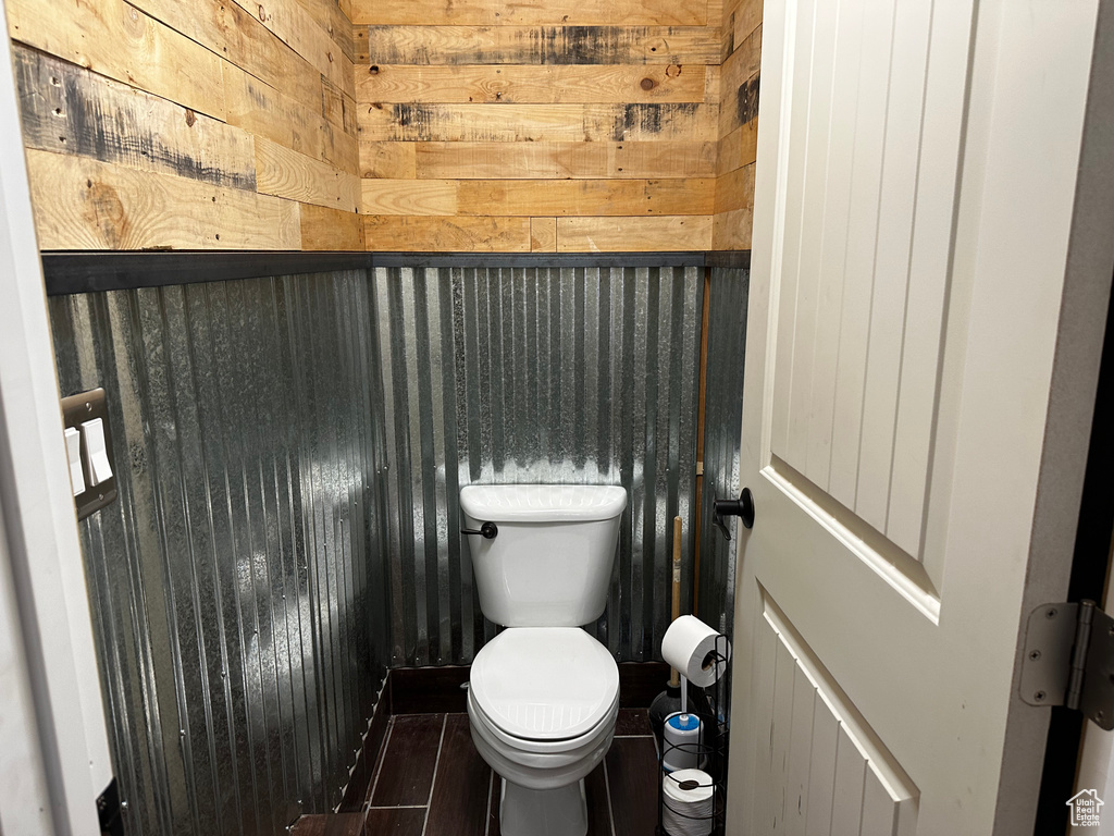 Bathroom featuring wooden walls, toilet, and tile flooring
