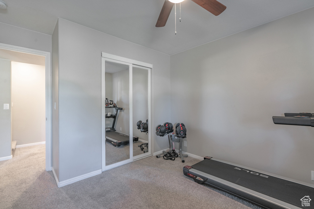 Workout room featuring ceiling fan and light colored carpet