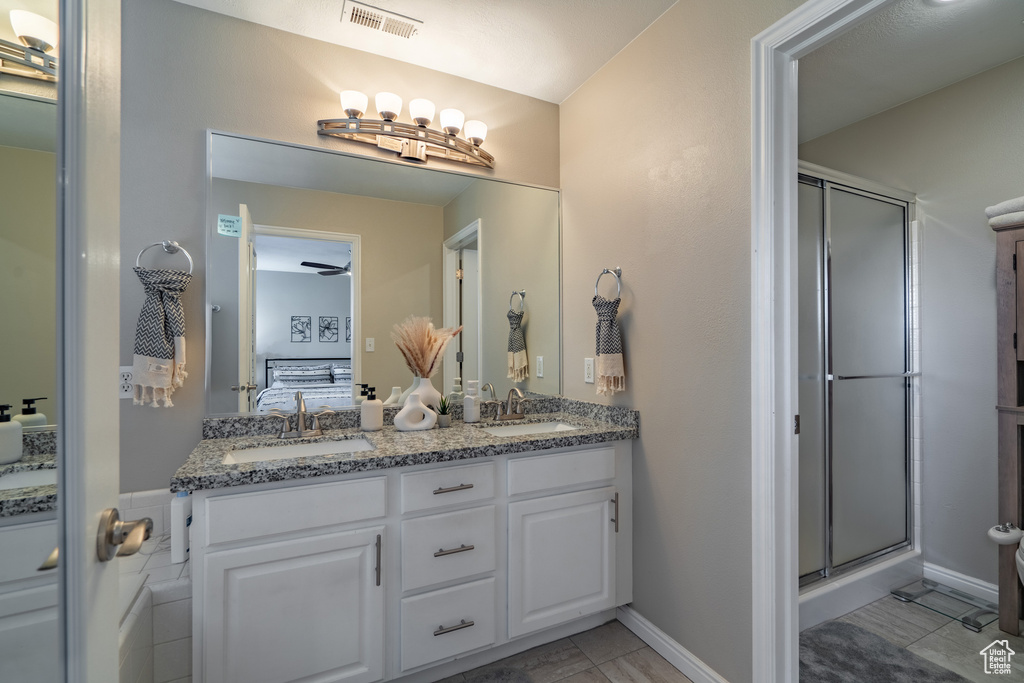 Bathroom with an enclosed shower, ceiling fan, tile floors, and dual bowl vanity