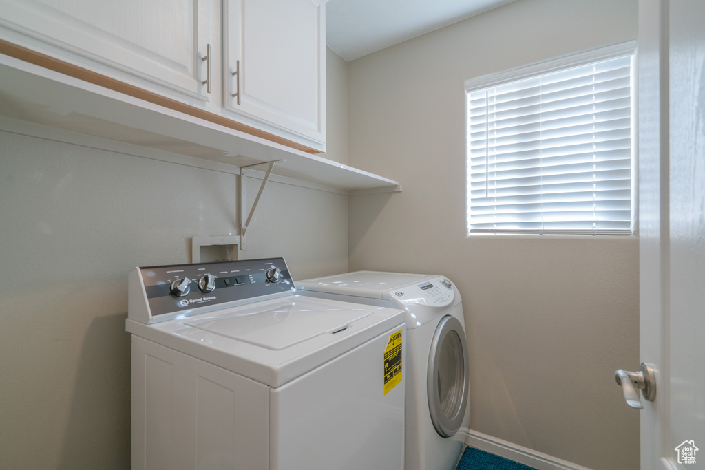 Clothes washing area featuring hookup for a washing machine, washer and dryer, and cabinets