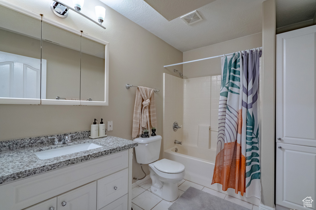 Full bathroom with large vanity, a textured ceiling, toilet, tile floors, and shower / bath combination with curtain