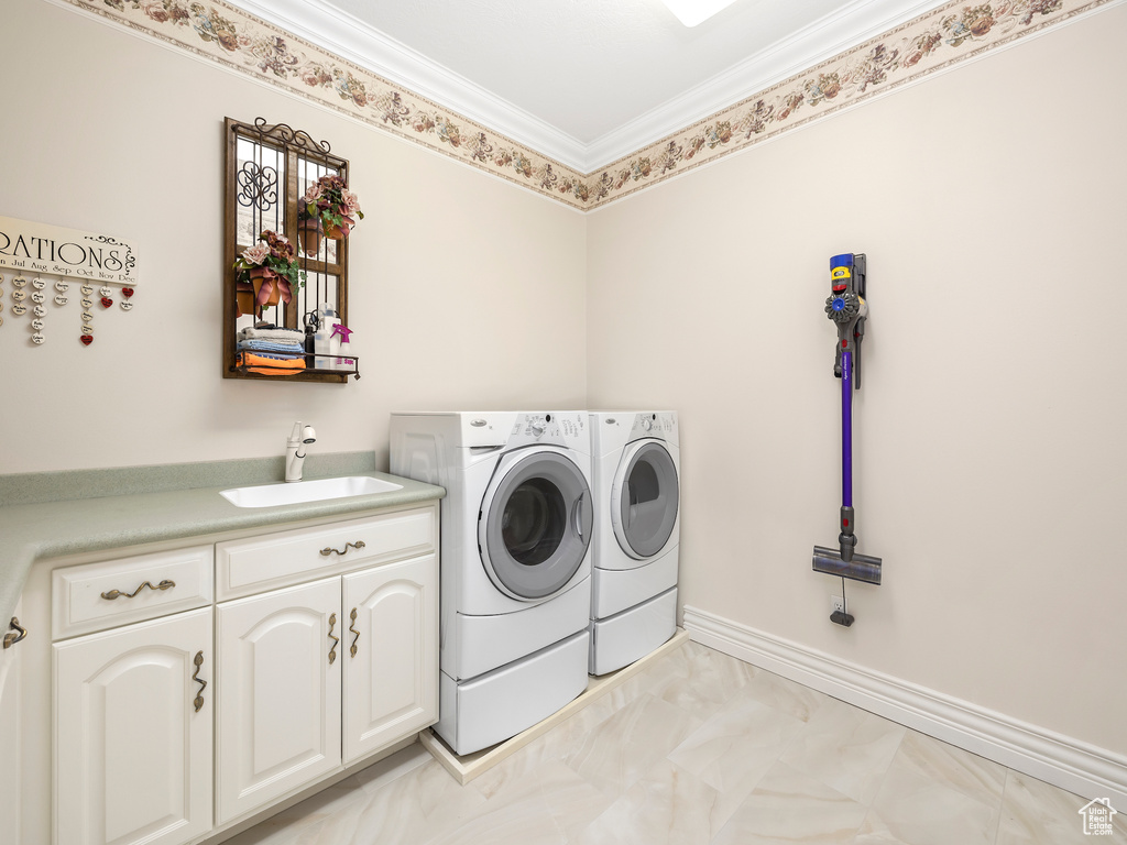 Laundry area featuring light tile flooring, crown molding, independent washer and dryer, sink, and cabinets