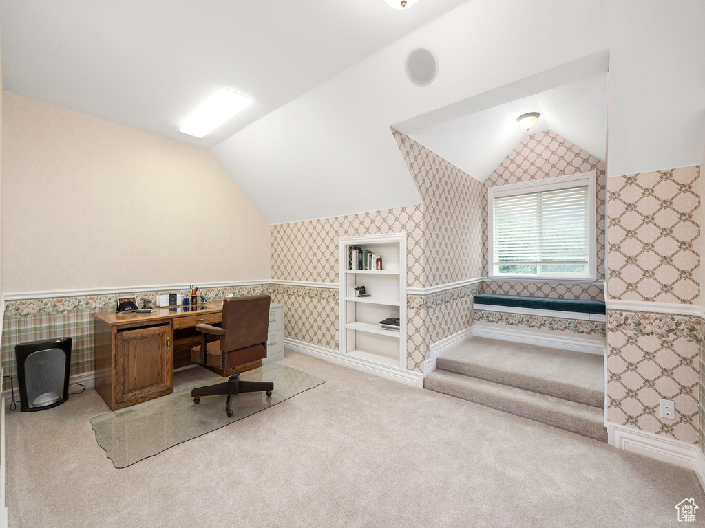 Office space featuring light colored carpet and vaulted ceiling