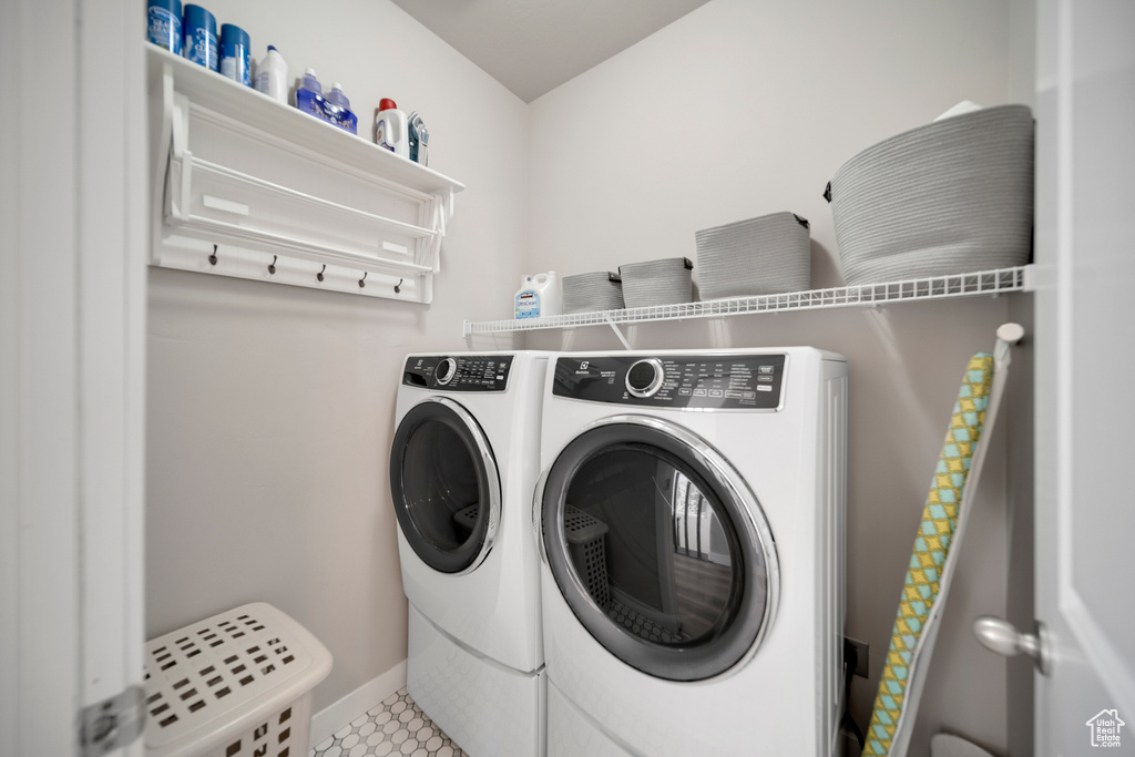 Washroom with tile floors and washing machine and clothes dryer