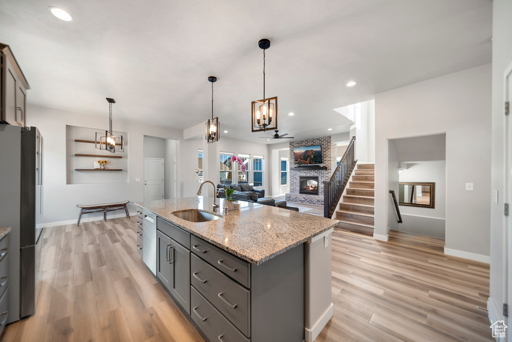 Kitchen featuring light hardwood / wood-style flooring, sink, decorative light fixtures, and a brick fireplace